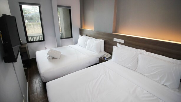 Une chambre d’hôtel avec deux lits, une télévision et une fenêtre donnant sur l’extérieur.