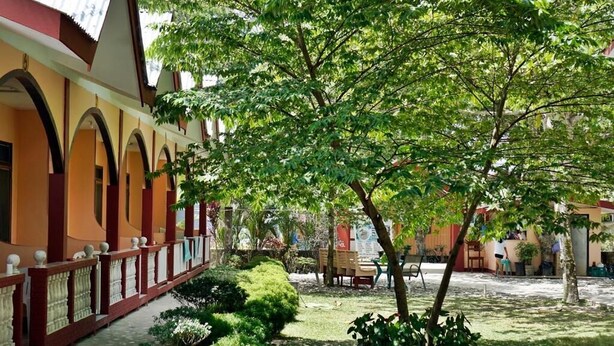 A courtyard with a covered walkway, potted plants, and a seating area. - Port Barton DIY (San Vicente)