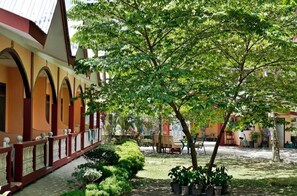 A courtyard with a covered walkway, potted plants, and a seating area. - Port Barton DIY (San Vicente)