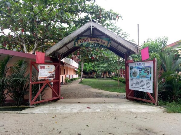 The entrance to JBR Tourist Inn with a covered walkway, surrounded by greenery and palm trees. - Port Barton DIY (San Vicente)
