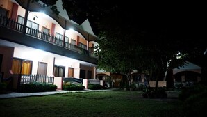 A multi-story hotel with balconies, a well-maintained lawn, and a tree in the foreground. - Port Barton DIY (San Vicente)