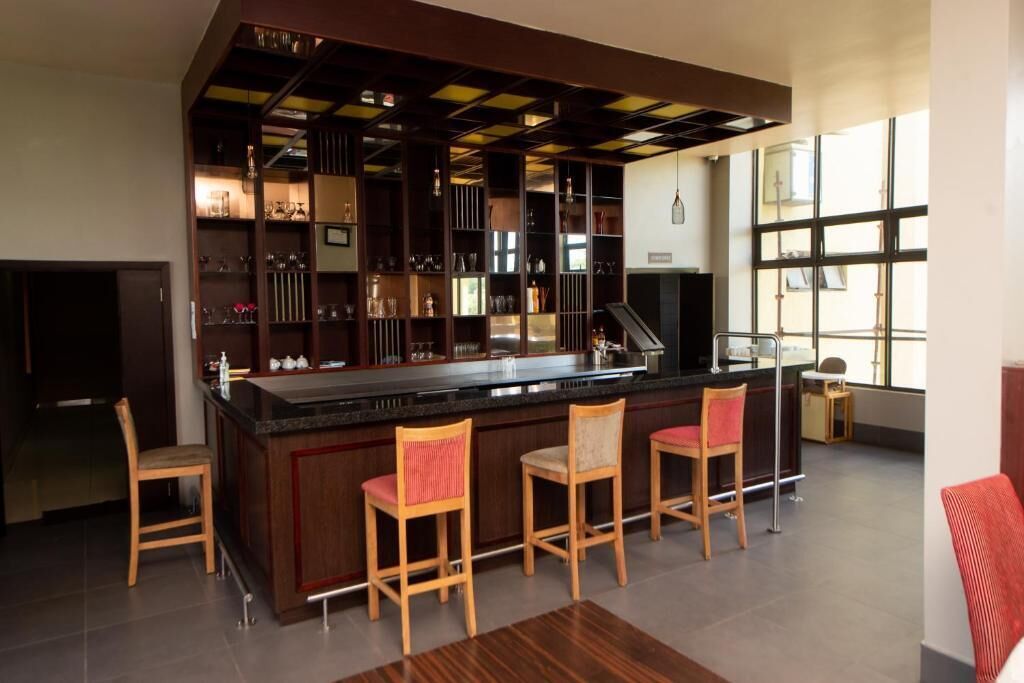 A bar area with a counter, bar stools, and shelves with glasses and bottles.
