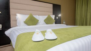A neatly made bed with a green bedspread, white pillows, and a headboard. - Crossroads Hotel Blantyre (Blantyre)