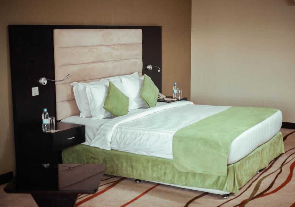 A hotel room with a bed, a nightstand, a chair, and a carpeted floor.