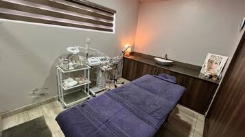 Guest room with a single bed, medical cart, and a small table with a sink.