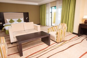 Una habitación de hotel con cama, sofá, mesita de café y una silla.