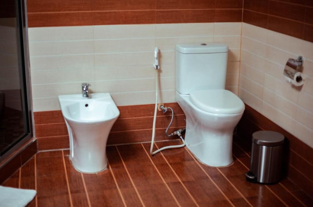 Un baño con bidé, inodoro y un cubo de basura.