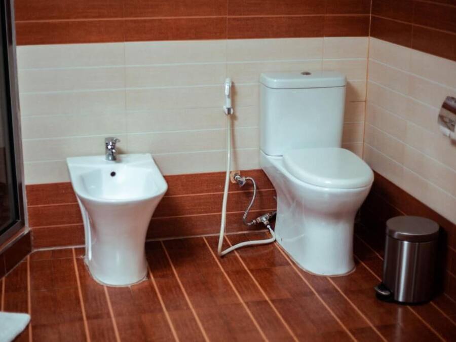Un baño con bidé, inodoro y un cubo de basura.