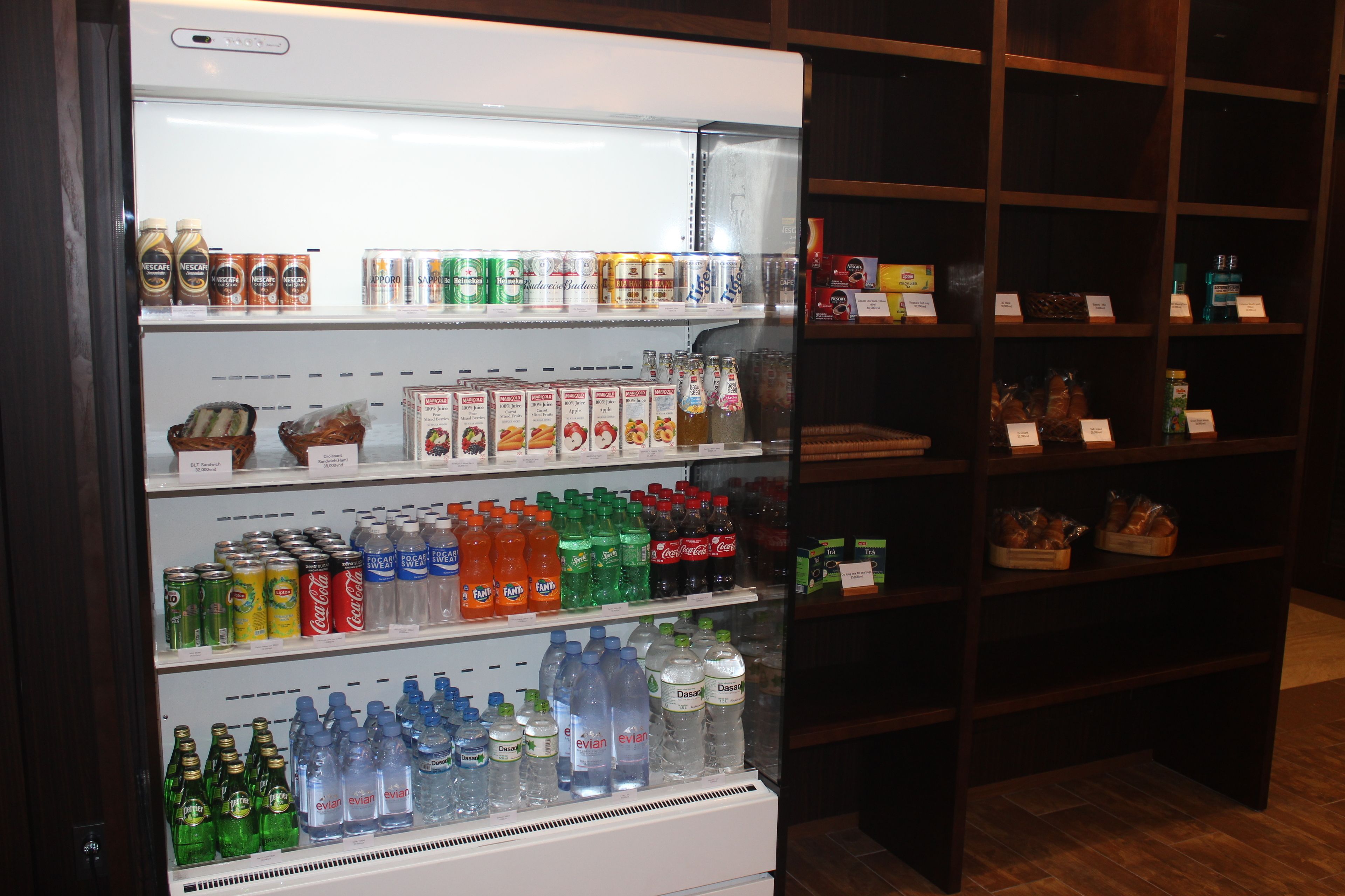 Un refrigerador para bebidas repleto de diversas opciones y un estante con productos envasados.