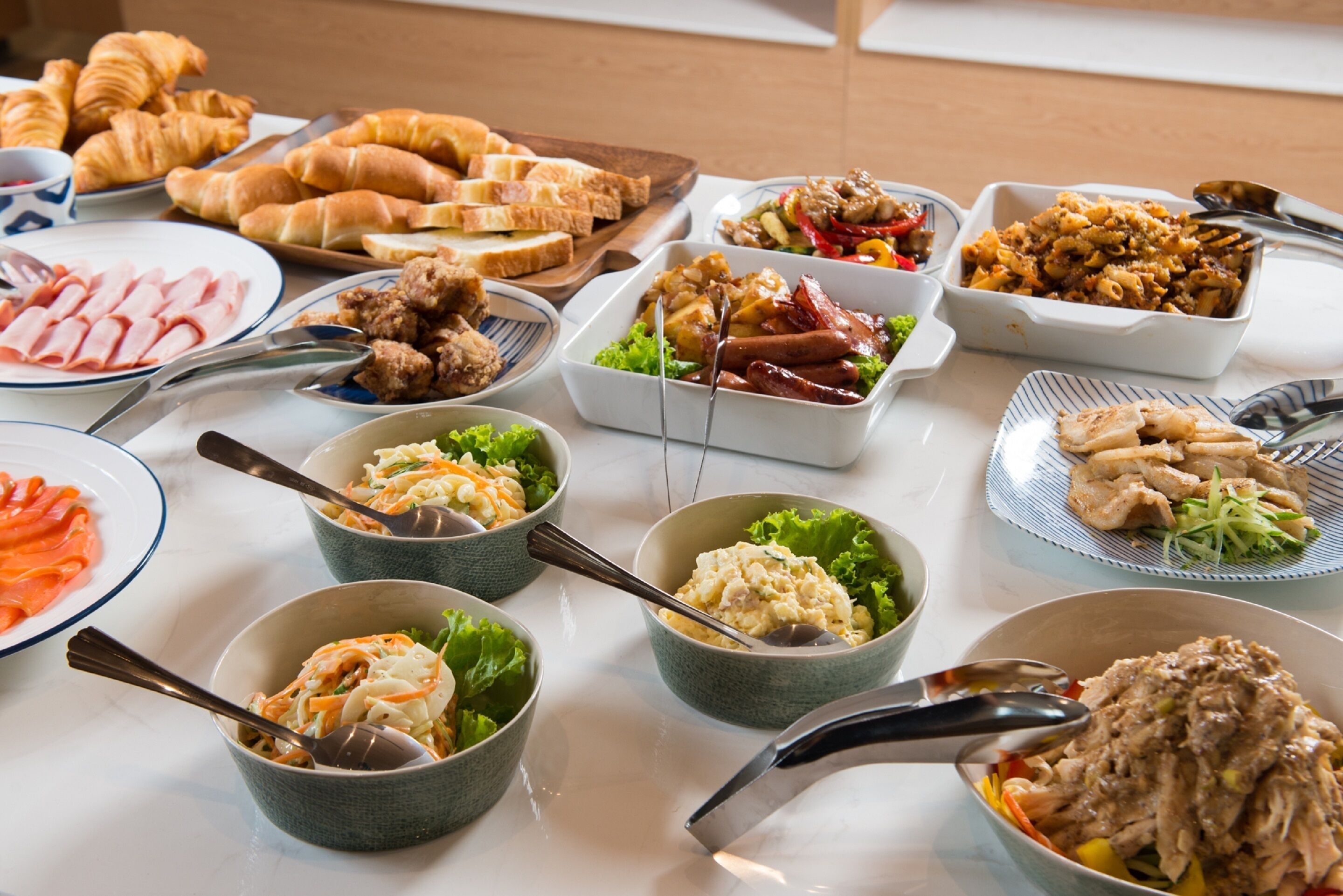 A buffet table with various dishes including meats, salads, and pastries.