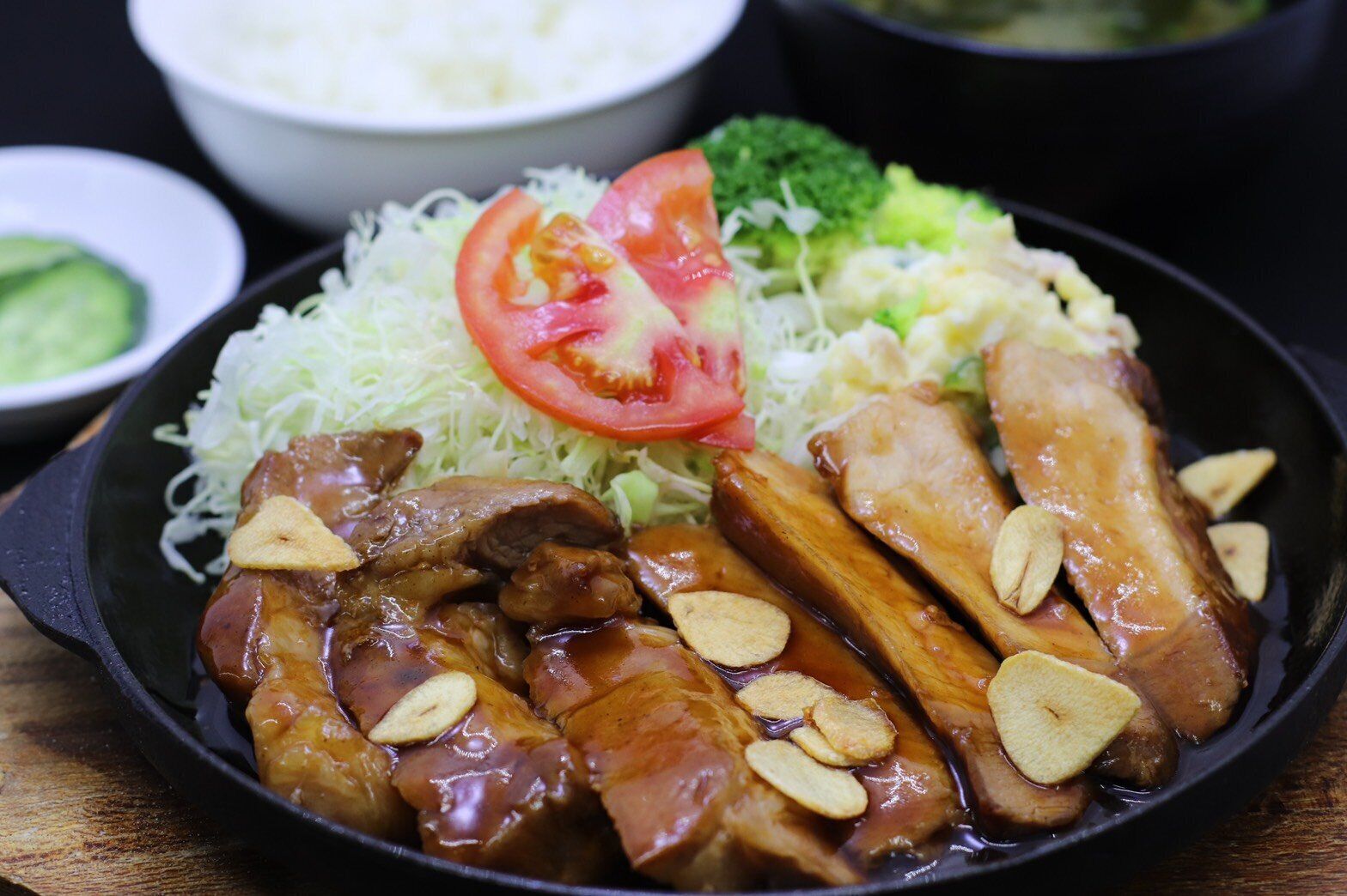 A plate of food with sliced meat, vegetables, and a side of rice.