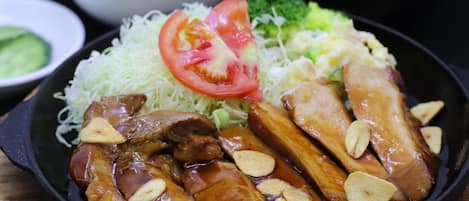 A plate of food with sliced meat, vegetables, and a side of rice.