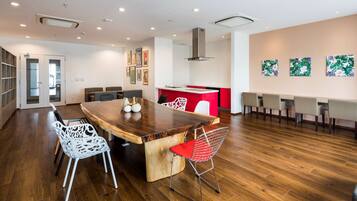A modern dining area with a wooden table, white chairs, and a red accent wall.