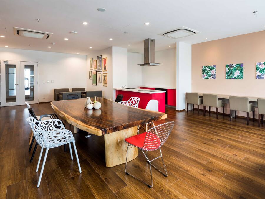 A modern dining area with a wooden table, white chairs, and a red accent wall.
