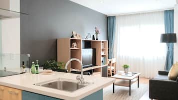 A modern apartment with a kitchen, dining area, and living room. It features a large window with curtains, a sofa, and a TV stand.