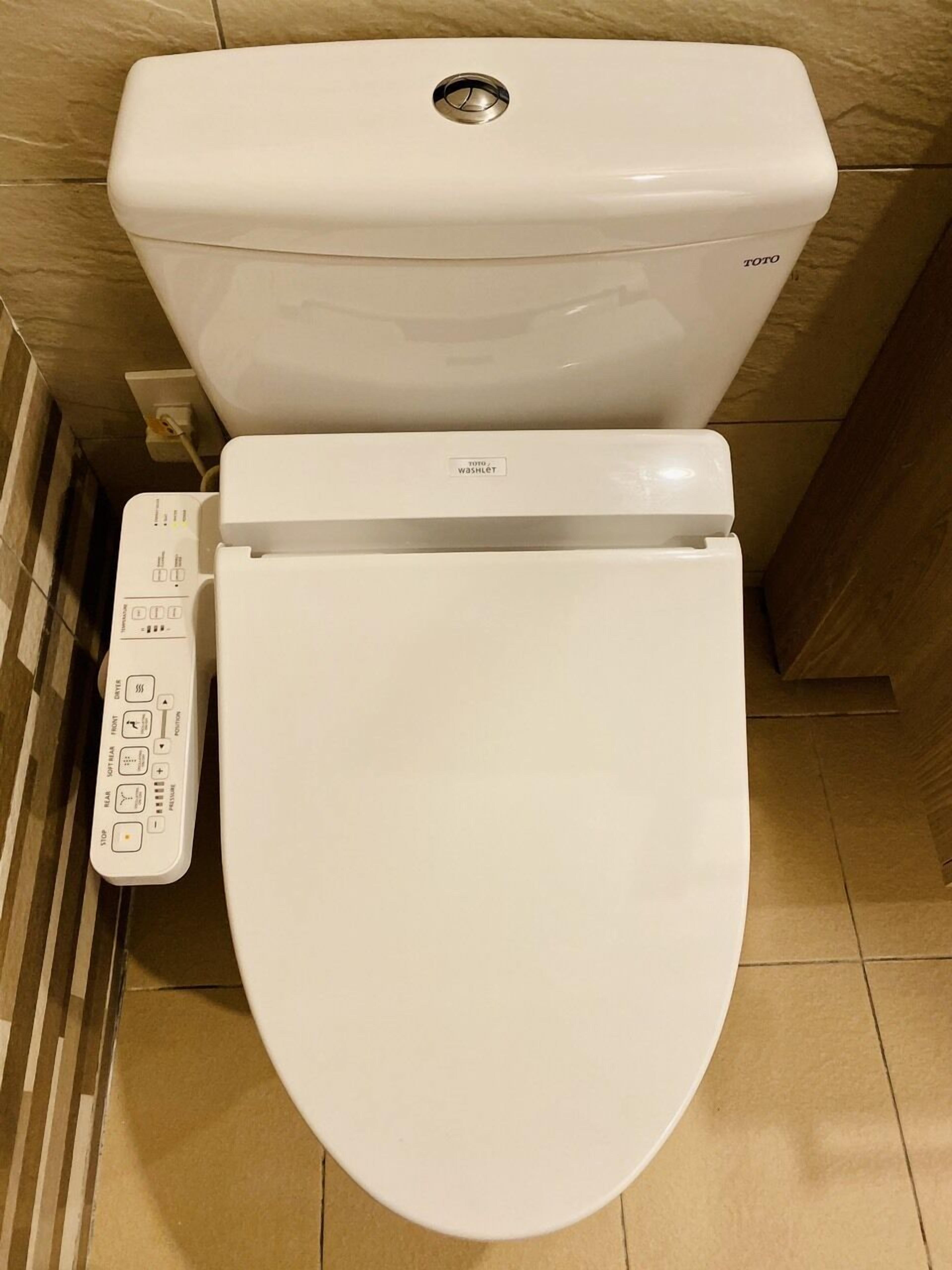 Een wit Toto toilet met een bedieningspaneel met knoppen voor spoelen, bidet en andere functies.