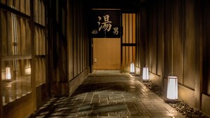 A corridor with tiled flooring and wooden walls, illuminated by wall-mounted lamps. - Roygent Parks Hanoi (Hanoi)