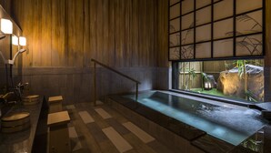 A traditional Japanese-style bathroom with a wooden interior, a stone sink, and a small indoor waterfall. - Roygent Parks Hanoi (Hanoi)