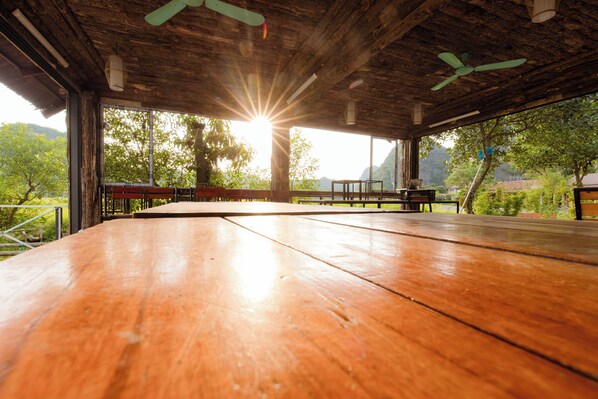 An open wooden deck with a view of a mountainous landscape. - Heritage Soul Bungalow Tam Coc (Nam Hoa Lu)
