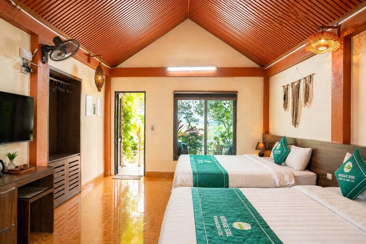 Une chambre d’hôtel avec deux lits, une télévision, un bureau et une vue sur la verdure.