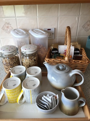 A tray with various kitchen items including jars, mugs, a teapot, and a basket with coffee products. - The Homer (Kilmuir)
