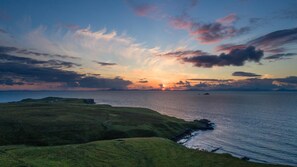 A coastal landscape with rolling hills and a calm sea. - The Homer (Kilmuir)