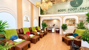 A Yomi foot and body spa with leather seating, plants, and a reception desk. - A25 Premium Hotel - 19 Cha Ca (Hanoi)