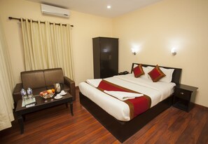 A hotel room with a bed, a sofa, a nightstand, a table with a coffee pot, and a wardrobe. - Hotel Dream City (Kathmandu)