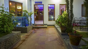 A hotel entrance with a sign reading "HOTEL DREAM CITY," a stone pathway, potted plants, and a small outdoor seating area. - Hotel Dream City (Kathmandu)
