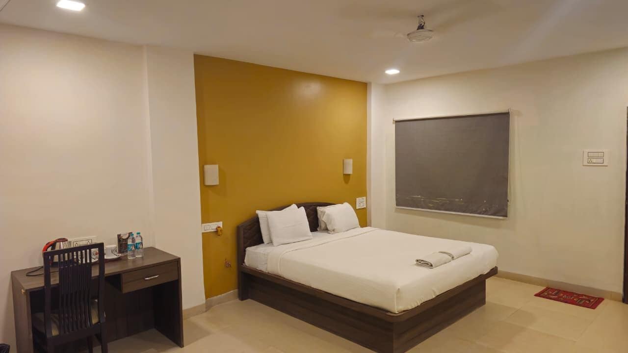 A hotel room with a bed, a desk, and a chair.