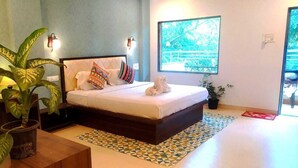 A bedroom with a bed, pillows, a potted plant, and a window with a view. - Hiranya Resorts (Chhatrapati Sambhajinagar)