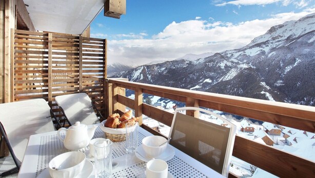 A balcony with a table set for breakfast, overlooking a snowy mountain landscape. - Chalet in Praroustan with Mountain Views (PRA LOUP 1500)