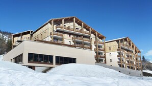 A multi-story hotel with wooden balconies and a modern facade. - Chalet in Praroustan with Mountain Views (PRA LOUP 1500)