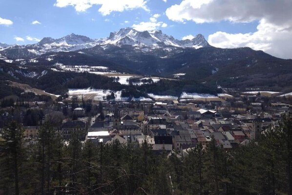 Un poble situat entre muntanyes amb cims nevats al fons.