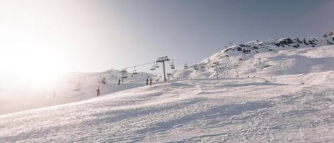 Een besneeuwde helling met skiliften en een heldere lucht.