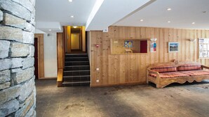 Ein Holzinnenraum mit einer Steinwand, einer Treppe und einem Bett mit Karo-Bettwäsche.
