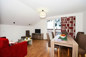 Ein modernes Wohnzimmer mit Essbereich, einem Fernseher und einem Balkon mit Blick.