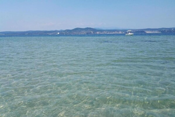Vista despejada de un mar tranquilo con tierra y edificios a lo lejos.