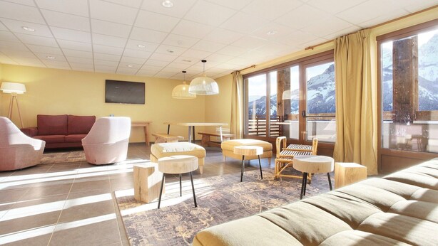 A modern hotel room with a large window offering a mountain view, a sofa, a dining table, and a TV. - Chalet in Praroustan with Mountain Views (PRA LOUP 1500)