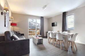 A modern living room with a sofa, a coffee table, and a dining area with chairs and a table.