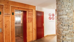 A wooden elevator with a red door, a reception sign, and a no-smoking, no-eating sign on the wall. - Chalet-Style Stay in Val Claret (Tignes)