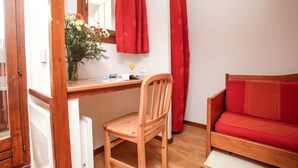 A room with a wooden desk, a chair, a red sofa, and a window with red curtains. - Chalet-Style Stay in Val Claret (Tignes)