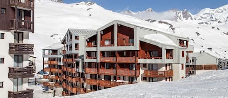 Ett hotell med flera våningar och balkonger, beläget med en snötäckt bergskedja som bakgrund.
