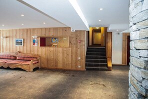 A wooden interior with a sofa, a staircase, and a stone wall.
