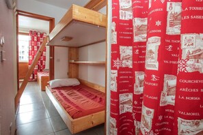 A room with a bunk bed, a wooden staircase, and a red patterned curtain. - Chalet in French Alps with Alpine Charm (Tignes)