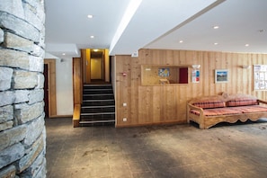 A wooden interior with a stone wall, a staircase, and a bed with plaid bedding. - Chalet in French Alps with Alpine Charm (Tignes)