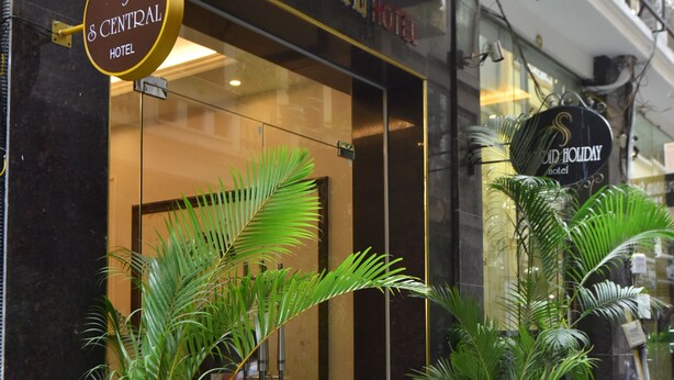 The exterior of the S Central Hotel with a prominent sign, large potted plants, and a glass entrance. - S Central Hotel & Spa (Hanoi)
