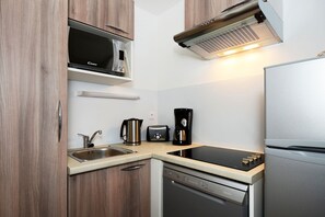 Eine kompakte Küche mit Mikrowelle, Toaster, Kaffeemaschine und Geschirrspüler.