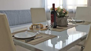 A dining table set with plates, cutlery, a bottle of wine, glasses, and a flower arrangement. - 03. Apartment (Signa)