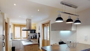 A modern kitchen with wooden cabinets, a central island, and pendant lighting.